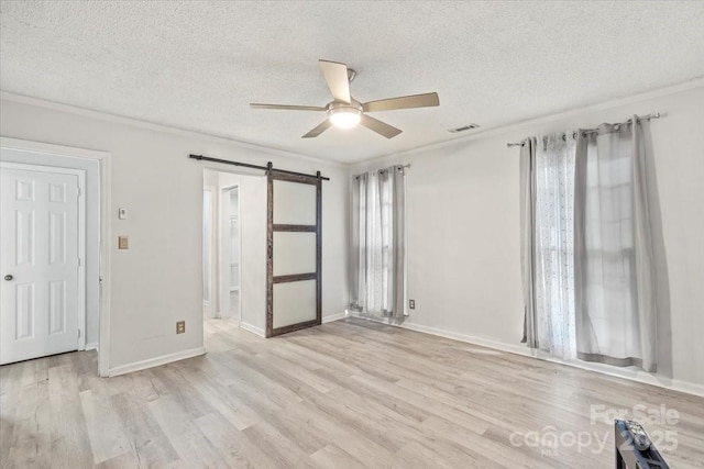 6500 Peacehaven Dr, Charlotte, NC 28214 - unfurnished bedroom with a barn door, light wood-type flooring, a textured ceiling, crown molding, and ceiling fan