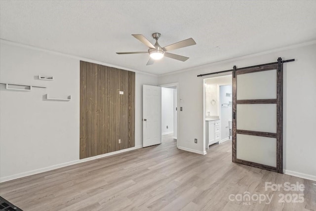 6500 Peacehaven Dr, Charlotte, NC 28214 - unfurnished bedroom with light wood finished floors, ornamental molding, a barn door, a textured ceiling, and connected bathroom