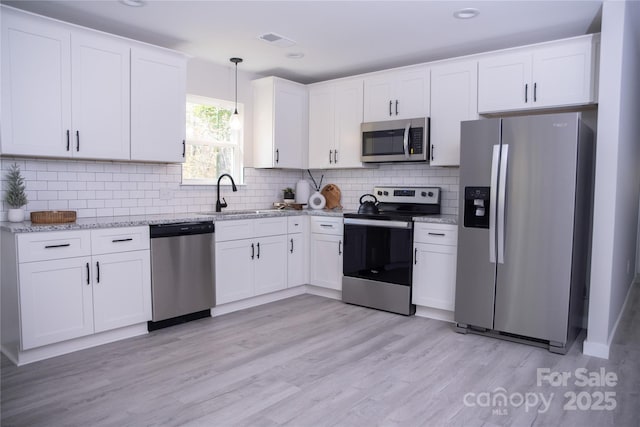 815 32nd St NE Unit 3, Conover, NC 28613 - kitchen featuring appliances with stainless steel finishes, white cabinets, light stone counters, pendant lighting, and decorative backsplash