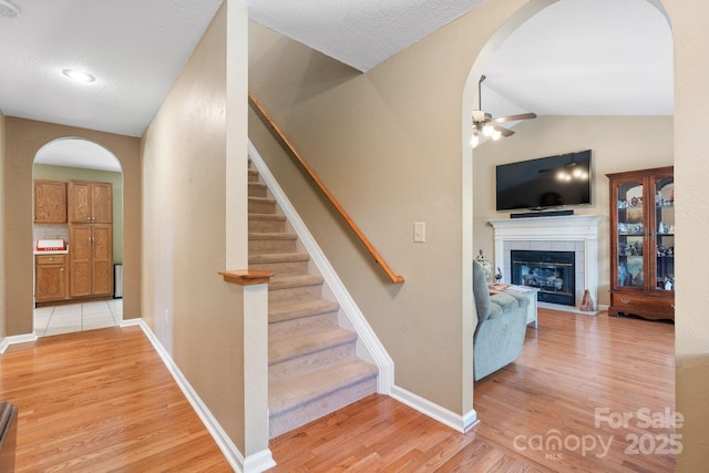 123 Clearwater Dr, Morganton, NC 28655 - stairway with a ceiling fan, arched walkways, wood finished floors, a tiled fireplace, and vaulted ceiling