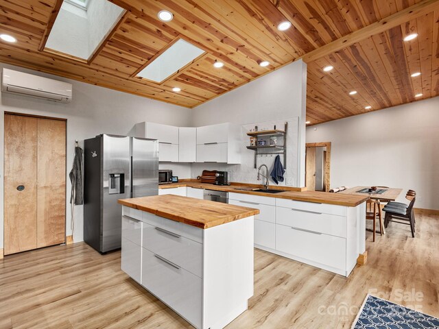 511 Emerald Mine Rd, Spruce Pine, NC 28777 - kitchen with butcher block countertops, appliances with stainless steel finishes, a wall mounted AC, modern cabinets, and a skylight