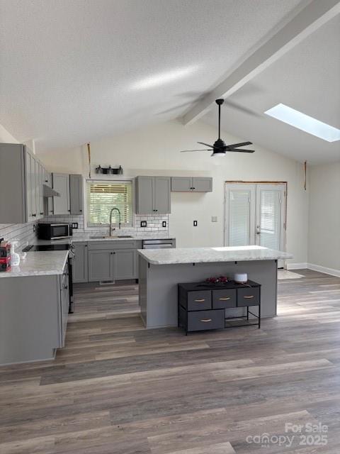 182 Redhawk Ln, Olin, NC 28660 - kitchen with gray cabinets, a center island, tasteful backsplash, dark wood finished floors, and appliances with stainless steel finishes
