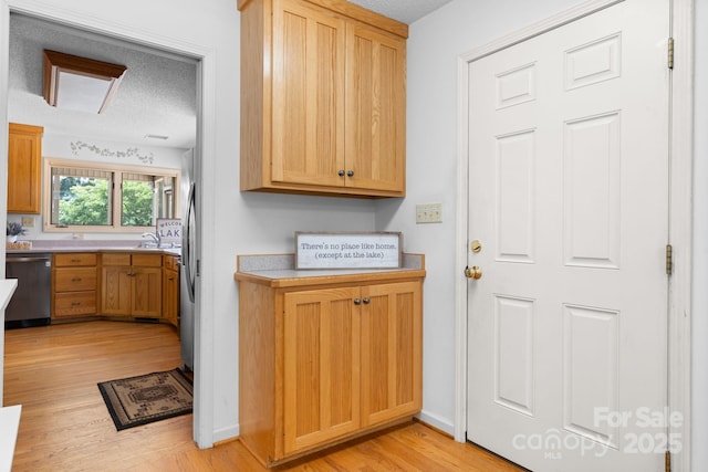 2066 Waterford Way, Morganton, NC 28655 - kitchen with stainless steel dishwasher, a textured ceiling, light countertops, and light wood finished floors