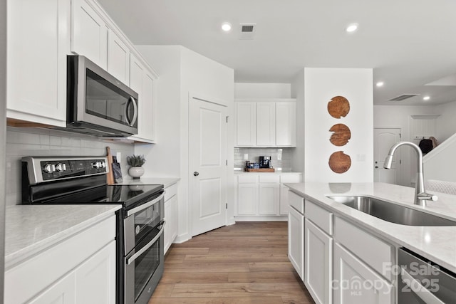 2589 Blue Sky Meadows Dr, Monroe, NC 28110 - kitchen featuring stainless steel appliances, light wood-style flooring, decorative backsplash, white cabinets, and recessed lighting