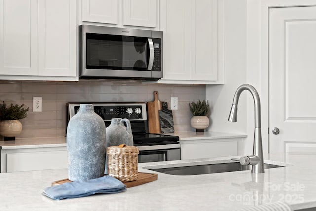 2589 Blue Sky Meadows Dr, Monroe, NC 28110 - detailed view of stainless steel appliances, tasteful backsplash, white cabinetry, and light stone countertops
