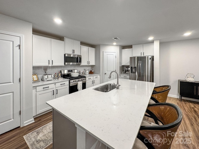2807 Oldfield Dr, Monroe, NC 28110 - kitchen featuring stainless steel appliances, dark wood finished floors, a breakfast bar, white cabinets, and recessed lighting