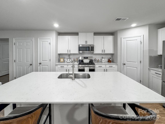 2807 Oldfield Dr, Monroe, NC 28110 - kitchen with stainless steel appliances, a kitchen bar, white cabinets, light stone countertops, and recessed lighting