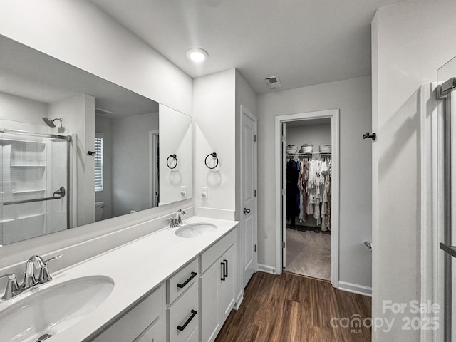 2807 Oldfield Dr, Monroe, NC 28110 - bathroom featuring a stall shower, wood finished floors, double vanity, and a spacious closet