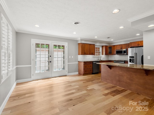1411 Kensington Rd Unit C-1, Hendersonville, NC 28791 - kitchen featuring appliances with stainless steel finishes, brown cabinets, a breakfast bar, a textured ceiling, and ornamental molding