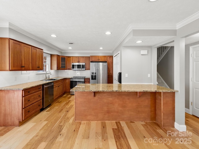 1411 Kensington Rd Unit C-1, Hendersonville, NC 28791 - kitchen featuring appliances with stainless steel finishes, a breakfast bar area, brown cabinetry, light wood-style flooring, and ornamental molding