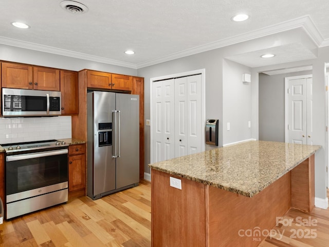 1411 Kensington Rd Unit C-1, Hendersonville, NC 28791 - kitchen with appliances with stainless steel finishes, light wood-style flooring, brown cabinets, tasteful backsplash, and light stone counters