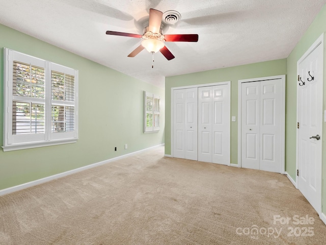 1411 Kensington Rd Unit C-1, Hendersonville, NC 28791 - unfurnished bedroom featuring two closets, carpet floors, ceiling fan, and a textured ceiling