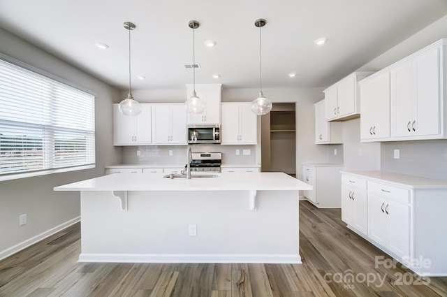 1700 Honey Trl, Monroe, NC 28112 - kitchen featuring appliances with stainless steel finishes, an island with sink, wood finished floors, backsplash, and recessed lighting