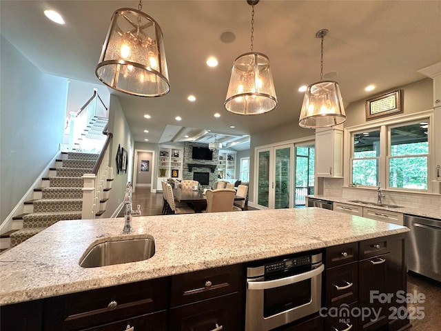 7816 Clovervale Dr, Waxhaw, NC 28173 - kitchen featuring stainless steel appliances, a fireplace, a center island with sink, open floor plan, and backsplash