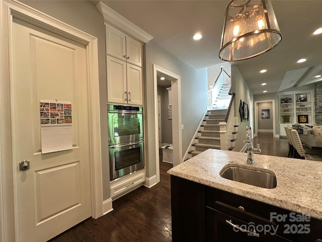 7816 Clovervale Dr, Waxhaw, NC 28173 - kitchen with double oven, white cabinets, light stone counters, dark wood finished floors, and open floor plan