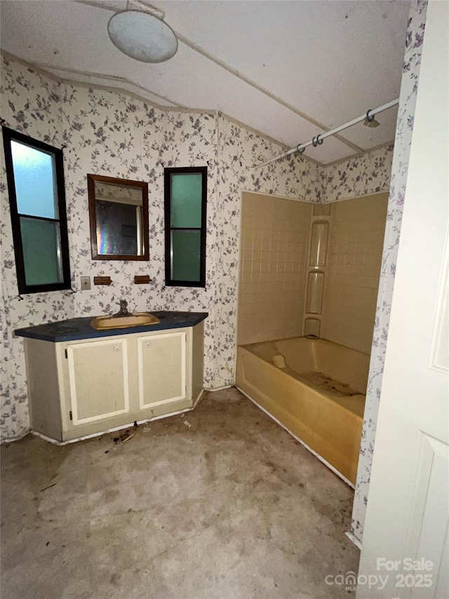 916 Steep Hill Rd, Belmont, NC 28012 - bathroom with lofted ceiling, vanity, washtub / shower combination, and wallpapered walls
