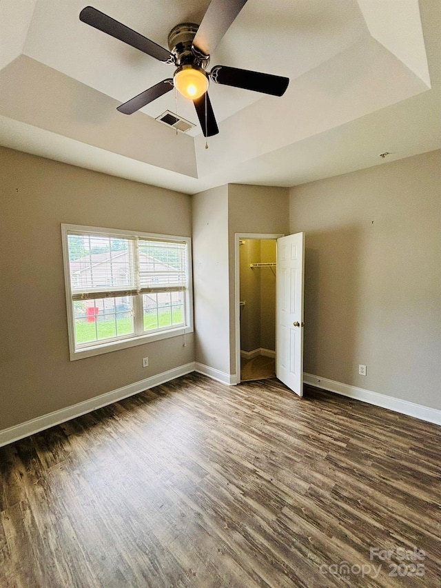 917 Shearer St Unit 15, Davidson, NC 28036 - unfurnished bedroom featuring a tray ceiling, dark wood-type flooring, ceiling fan, and a walk in closet