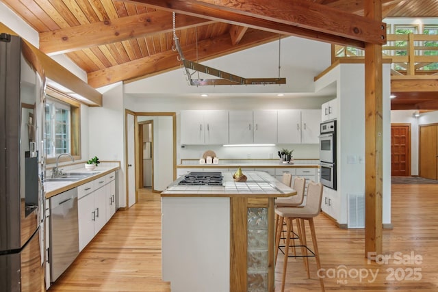 295 Dills Rd, Bryson City, NC 28713 - kitchen featuring stainless steel appliances, tile counters, a breakfast bar, light wood-type flooring, and wooden ceiling