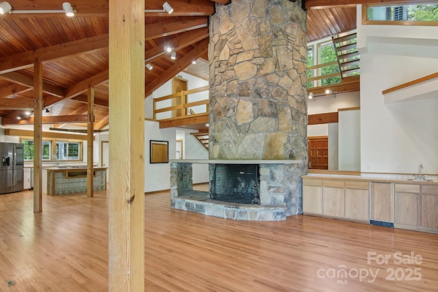 295 Dills Rd, Bryson City, NC 28713 - unfurnished living room with wood finished floors, a wood ceiling with exposed beams, high vaulted ceiling, a stone fireplace, and decorative columns