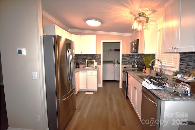 6264 Burnhurst Ln, Denver, NC 28037 - kitchen with washer and dryer, appliances with stainless steel finishes, tasteful backsplash, crown molding, and wood finished floors