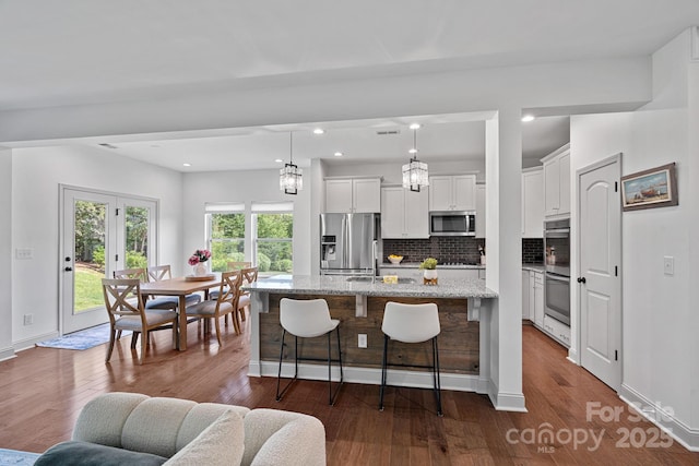 161 Oxford Dr, Mooresville, NC 28115 - kitchen featuring stainless steel appliances, dark wood-style floors, a center island with sink, decorative backsplash, and recessed lighting