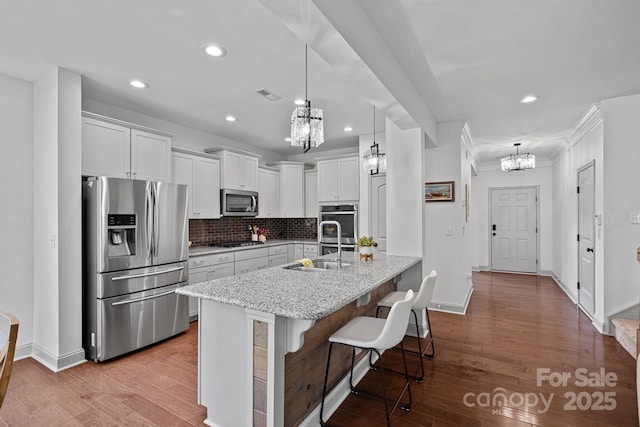 161 Oxford Dr, Mooresville, NC 28115 - kitchen featuring appliances with stainless steel finishes, a chandelier, light stone counters, a kitchen breakfast bar, and decorative backsplash