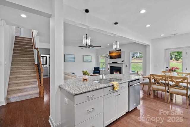 161 Oxford Dr, Mooresville, NC 28115 - kitchen featuring dishwasher, a ceiling fan, a lit fireplace, wood finished floors, and light stone countertops