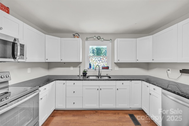 369 Birch Circle Dr, Hudson, NC 28638 - kitchen featuring stainless steel appliances, white cabinetry, light wood-style flooring, and dark stone counters