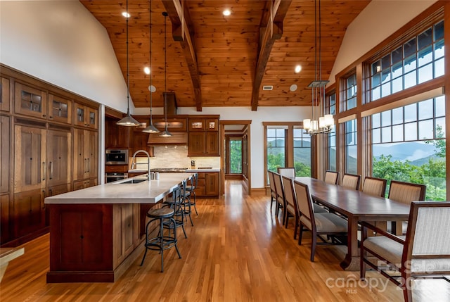 14 Clear Fork Ln, Fairview, NC 28730 - kitchen featuring a wooden ceiling with exposed beams, high vaulted ceiling, light wood finished floors, a kitchen island with sink, and decorative backsplash