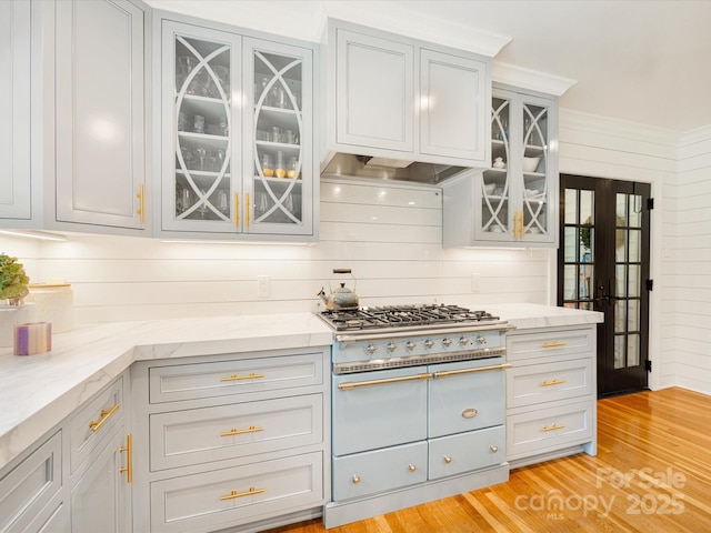 2912 Wheelock Rd, Charlotte, NC 28211 - kitchen featuring range with two ovens, glass insert cabinets, light stone countertops, light wood-style flooring, and exhaust hood