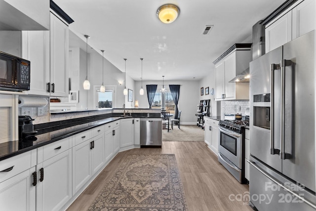 543 Muirfield Way, Salisbury, NC 28144 - kitchen with appliances with stainless steel finishes, a peninsula, light wood-style flooring, tasteful backsplash, and hanging light fixtures
