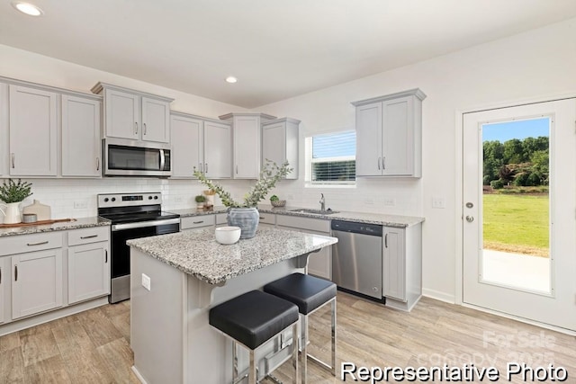 130 Fairfield Dr Unit 20, Troutman, NC 28166 - kitchen with appliances with stainless steel finishes, gray cabinetry, a kitchen breakfast bar, tasteful backsplash, and a kitchen island