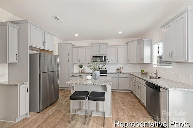 130 Fairfield Dr Unit 20, Troutman, NC 28166 - kitchen with appliances with stainless steel finishes, a kitchen island, light wood finished floors, decorative backsplash, and light stone countertops