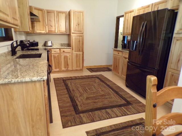 140 Beechwood Cir, Hendersonville, NC 28739 - kitchen with black fridge with ice dispenser, under cabinet range hood, light stone counters, and light brown cabinets