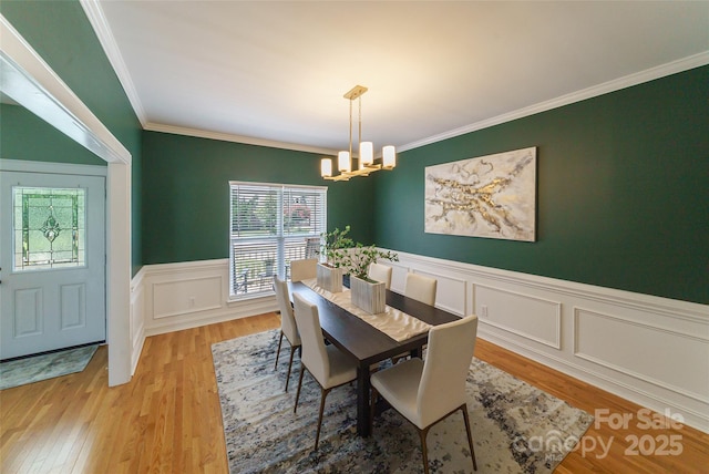 8509 Castle Cliff Dr, Matthews, NC 28105 - dining area with a chandelier, wood finished floors, wainscoting, crown molding, and a decorative wall
