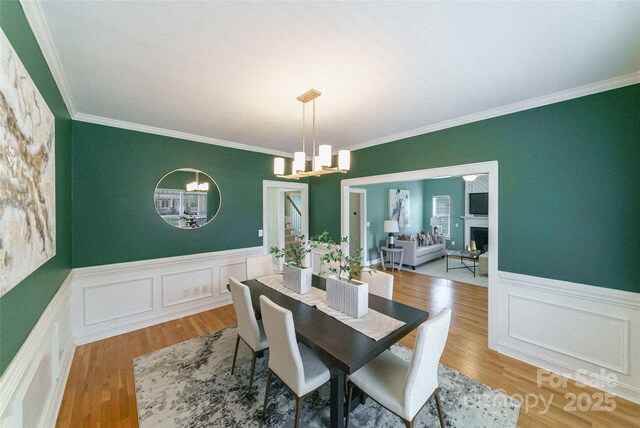 8509 Castle Cliff Dr, Matthews, NC 28105 - dining room featuring a chandelier, a wainscoted wall, a decorative wall, ornamental molding, and a fireplace
