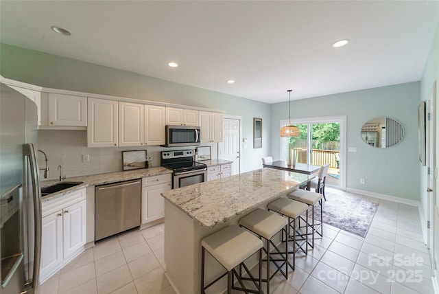 8509 Castle Cliff Dr, Matthews, NC 28105 - kitchen featuring appliances with stainless steel finishes, white cabinets, a kitchen bar, light tile patterned floors, and light stone counters