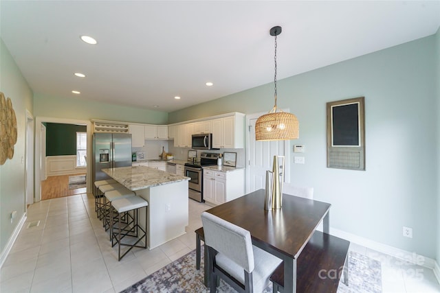 8509 Castle Cliff Dr, Matthews, NC 28105 - kitchen with appliances with stainless steel finishes, a kitchen breakfast bar, white cabinets, a kitchen island, and light stone counters