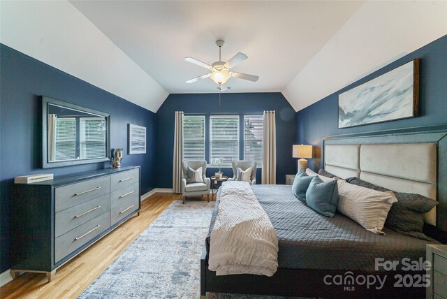 8509 Castle Cliff Dr, Matthews, NC 28105 - bedroom featuring multiple windows, vaulted ceiling, light wood-style floors, and a ceiling fan