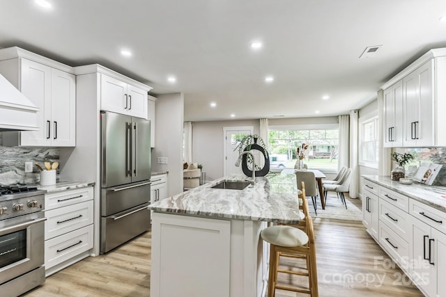 1208 Tarrington Ave, Charlotte, NC 28205 - kitchen with appliances with stainless steel finishes, decorative backsplash, light wood-style floors, white cabinets, and recessed lighting