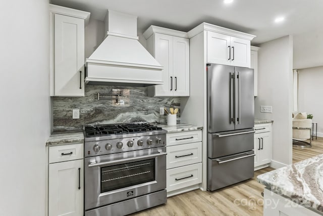 1208 Tarrington Ave, Charlotte, NC 28205 - kitchen featuring high quality appliances, custom exhaust hood, white cabinets, backsplash, and light wood-style floors