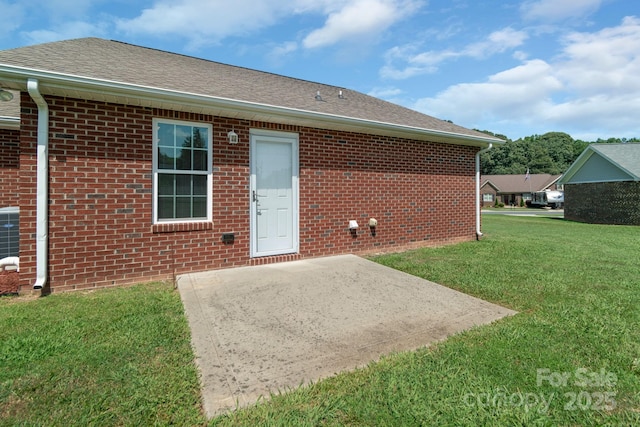 169 Abigail Ln, Locust, NC 28097 - rear view of house featuring a patio area, a lawn, brick siding, and roof with shingles