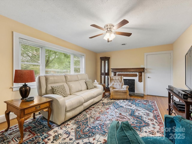 209 11th St, Spencer, NC 28159 - living room with ceiling fan, light wood-style flooring, a textured ceiling, and a brick fireplace