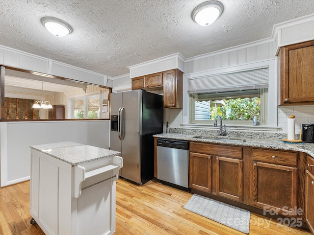 209 11th St, Spencer, NC 28159 - kitchen with ornamental molding, appliances with stainless steel finishes, light wood-style flooring, a textured ceiling, and brown cabinets
