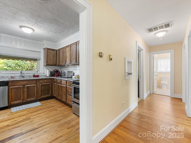 209 11th St, Spencer, NC 28159 - kitchen with light wood-type flooring, light stone countertops, appliances with stainless steel finishes, a textured ceiling, and backsplash