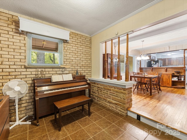 209 11th St, Spencer, NC 28159 - sitting room with a textured ceiling, a chandelier, brick wall, ornamental molding, and tile patterned flooring