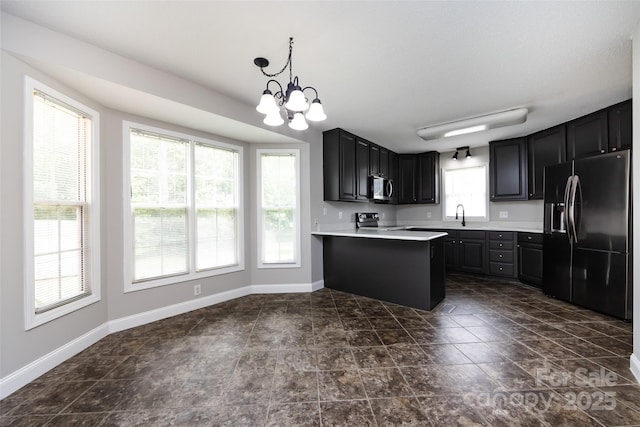 1309 Stonewyck Dr, Salisbury, NC 28146 - kitchen featuring appliances with stainless steel finishes, a peninsula, light countertops, a chandelier, and dark cabinetry