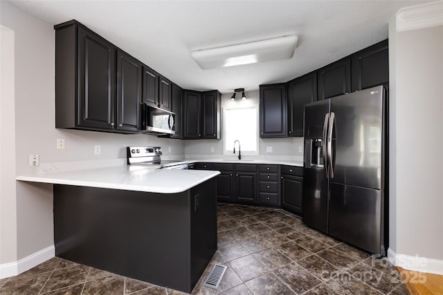 1309 Stonewyck Dr, Salisbury, NC 28146 - kitchen featuring appliances with stainless steel finishes, a peninsula, light countertops, and dark cabinets