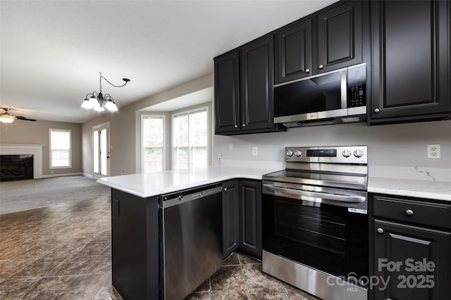 1309 Stonewyck Dr, Salisbury, NC 28146 - kitchen featuring appliances with stainless steel finishes, dark cabinets, open floor plan, a peninsula, and a premium fireplace