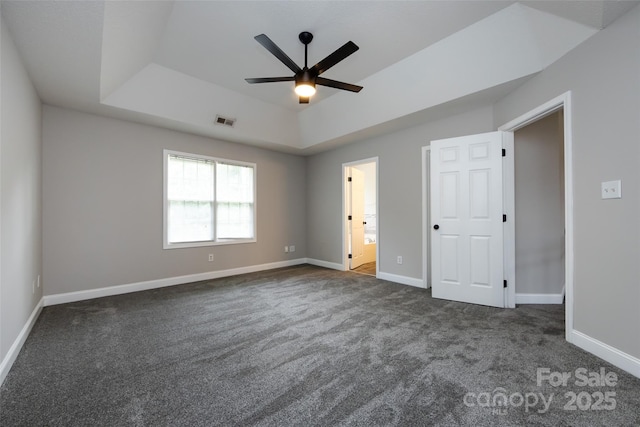 1309 Stonewyck Dr, Salisbury, NC 28146 - unfurnished bedroom featuring a tray ceiling, dark carpet, ceiling fan, and connected bathroom